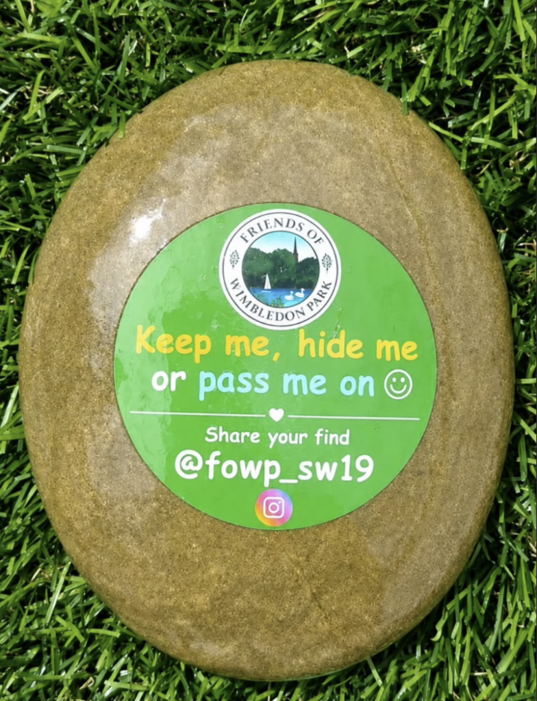 A painted pebble with Friends of Wimbledon Park Logo and text saying "Keep me, hide me or pass me on"
